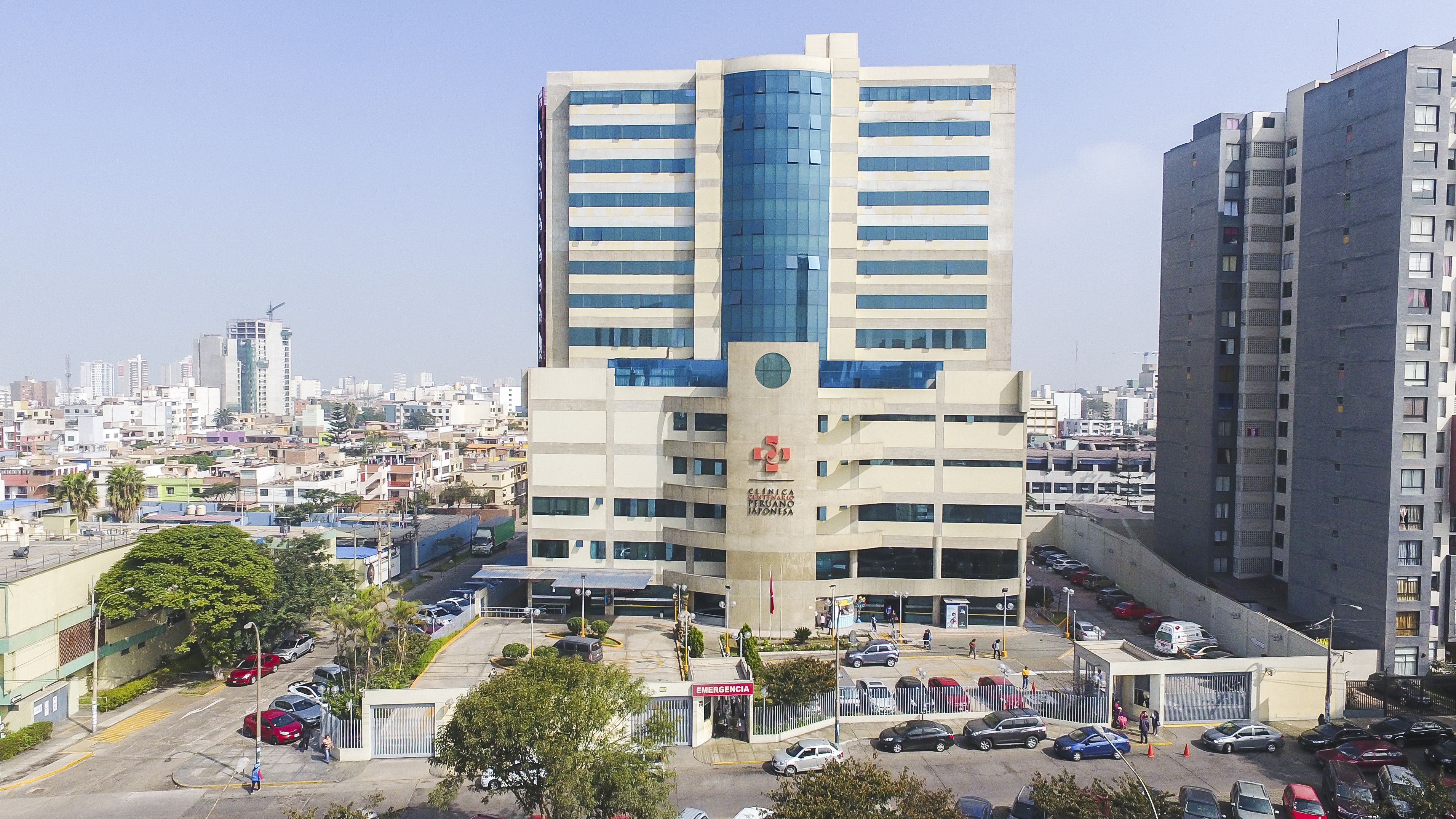 Médico especialista en bata blanca revisando a un paciente adulto en consultorio moderno de la Clínica Centenario Peruano Japonesa en Pueblo Libre, Lima