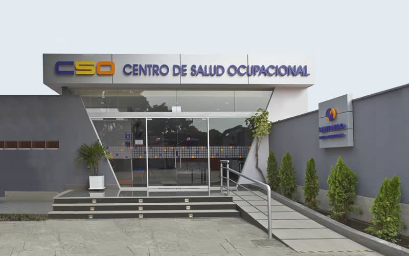 Médico ocupacional revisando los resultados de una audiometría a un trabajador en una sala de evaluación clínica del Centro de Salud Ocupacional en Perú